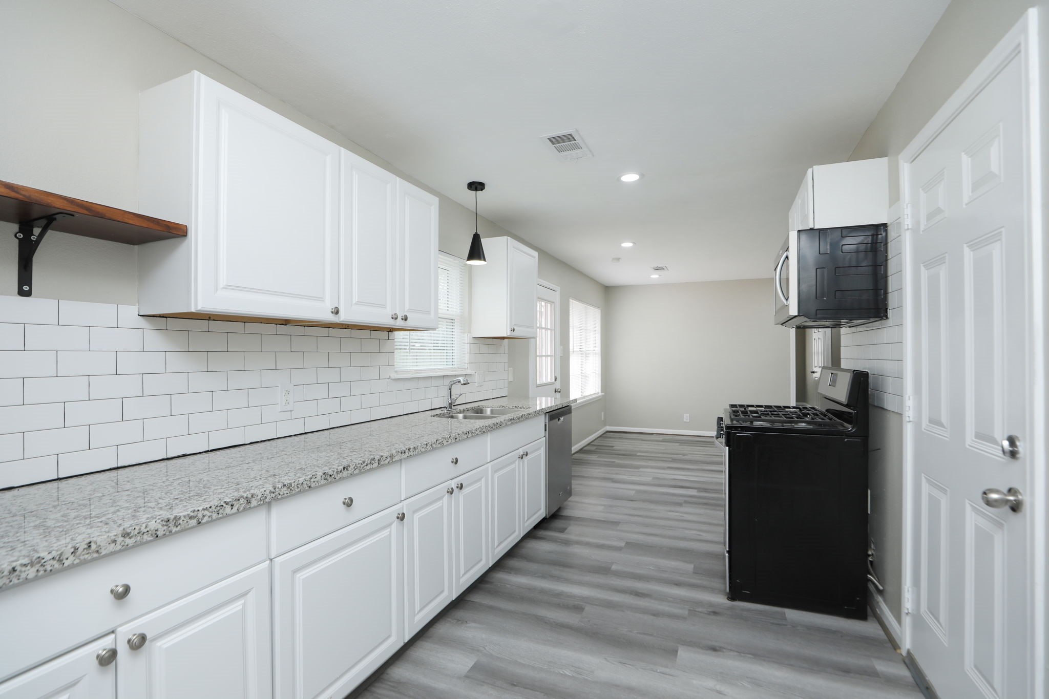 9211 Vinearbor Street Houston, TX 77033 - Photo 16 of 33 a kitchen with granite countertop white cabinets and black stainless steel appliances