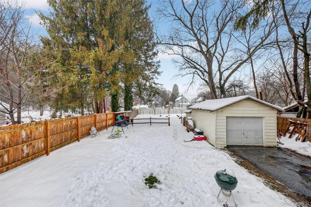 a view of a white house with a large tree and wooden fence