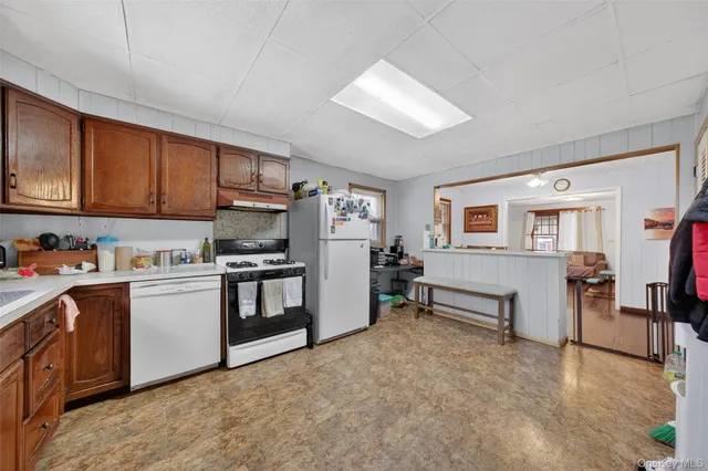 a kitchen with stainless steel appliances granite countertop a stove top oven a sink dishwasher and a refrigerator with wooden cabinets