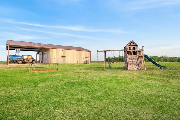 a view of a big house with a big yard and large trees