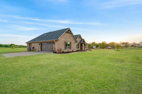 a view of a house with a big yard and large trees