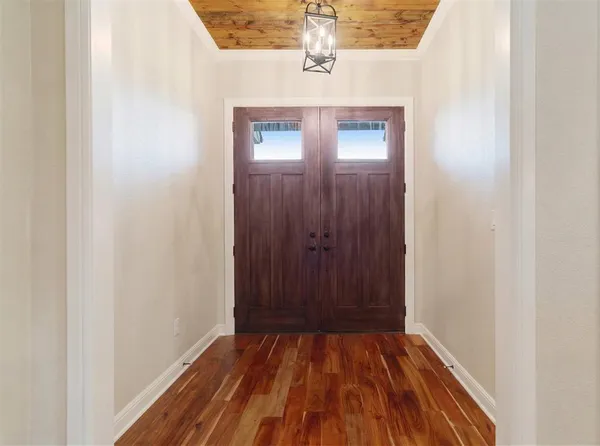 a view of a hallway with wooden floor and a bathroom