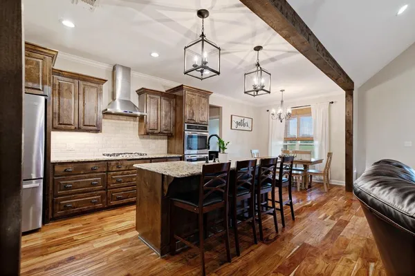 a kitchen with stainless steel appliances granite countertop a stove top oven a dining table and chairs with wooden floor
