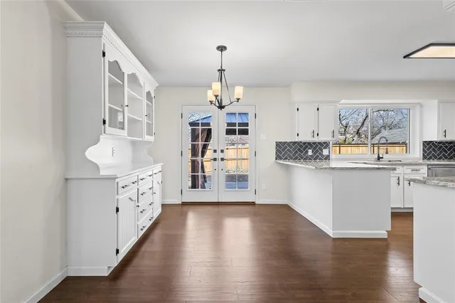 a kitchen with granite countertop a stove top oven a sink a dining table and chairs