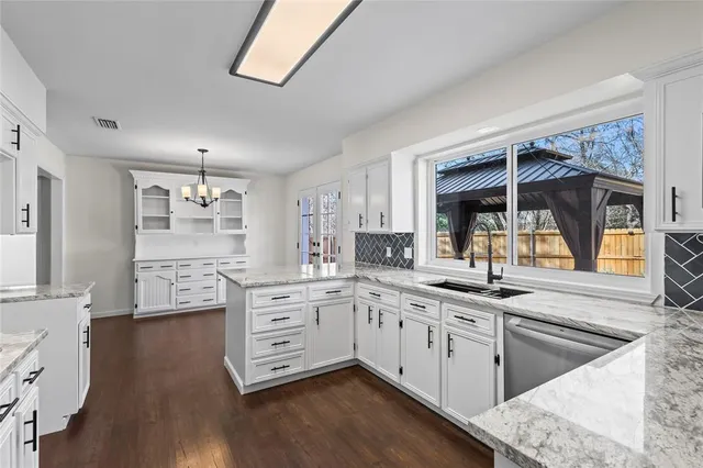 a kitchen with stainless steel appliances granite countertop a stove and white cabinets next to a window
