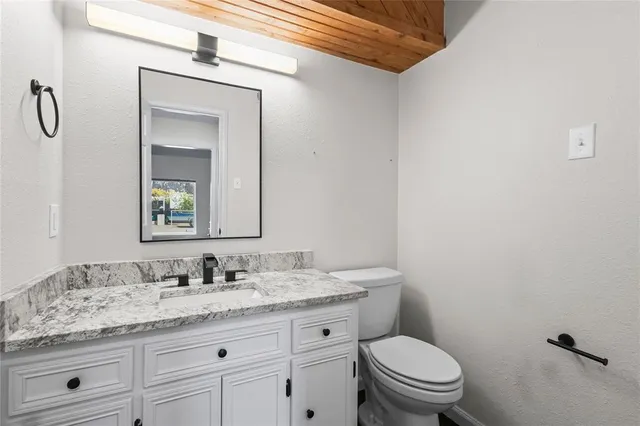 a bathroom with a granite countertop toilet sink and mirror