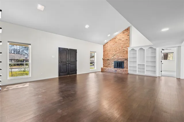 an empty room with wooden floor and fireplace