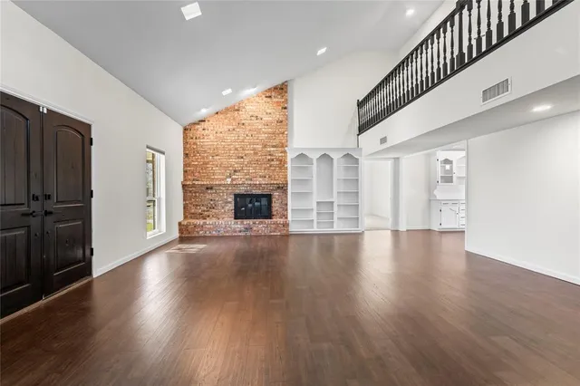 an empty room with wooden floor fireplace and windows