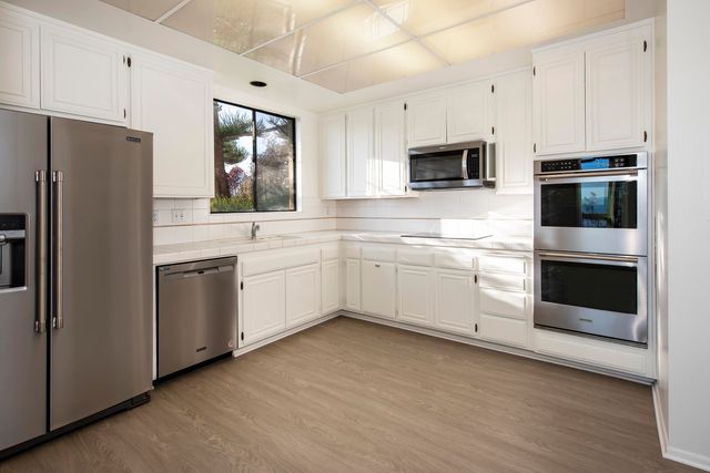 a kitchen with white cabinets and stainless steel appliances