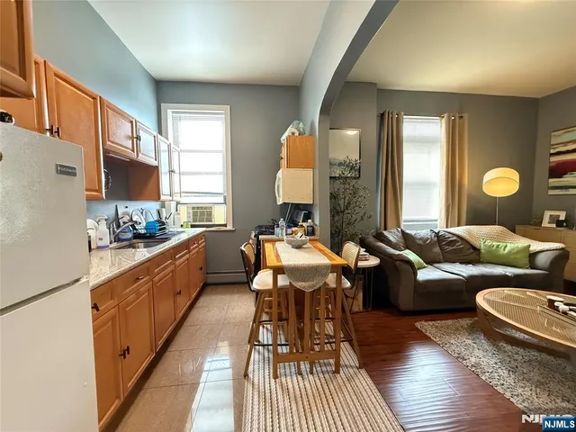 a large living room with stainless steel appliances granite countertop furniture a rug a lamp and a window