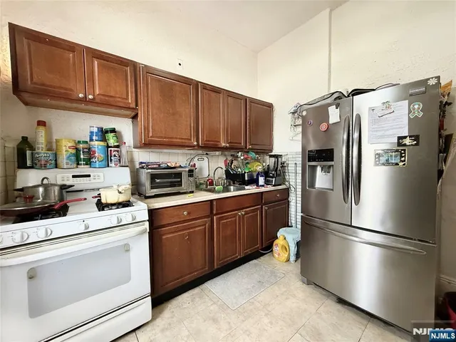 a kitchen with stainless steel appliances granite countertop a refrigerator sink stove and cabinets