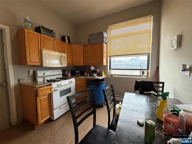 a kitchen with stainless steel appliances granite countertop a stove top oven a sink a dining table and chairs with wooden floor