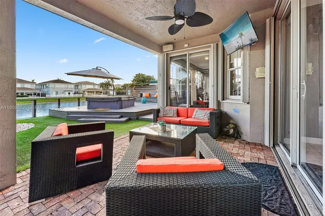 a view of a patio with couches chairs and a table and chairs with wooden floor and fence