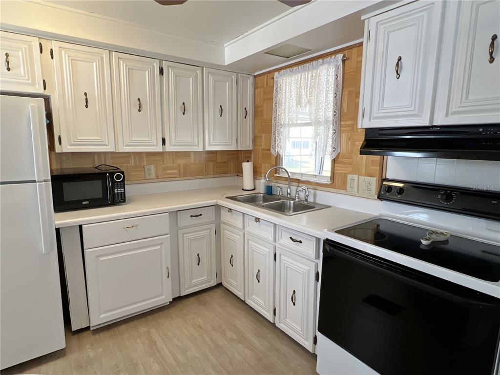 7181 Mt Hawthorne Road Northeast, Unit 590 St. Petersburg, FL 33702 - Photo 4 of 16 a kitchen with white cabinets and white appliances