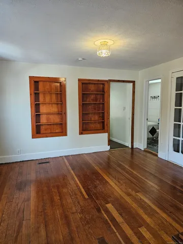a view of an empty room with wooden floor and window