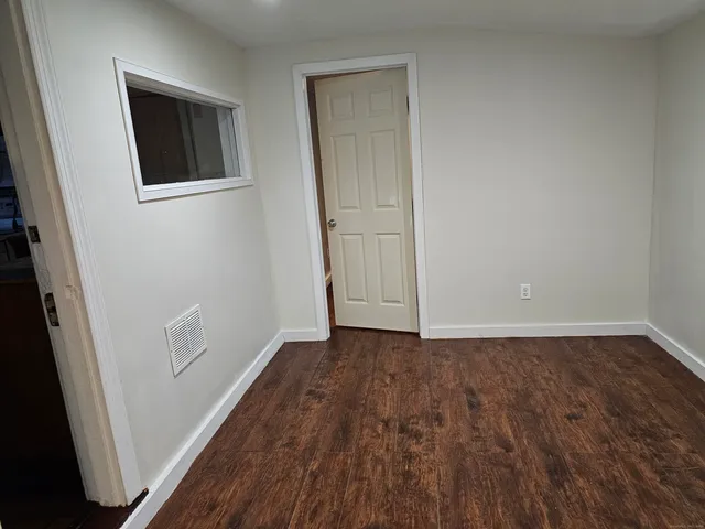 a view of an empty room with wooden floor and closet