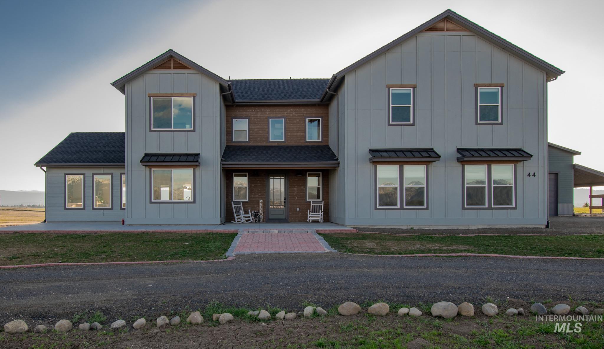 Contemporary farmhouse-style exterior featuring vertical siding, a central brick facade, multiple gables, a covered entry, and dark-framed windows