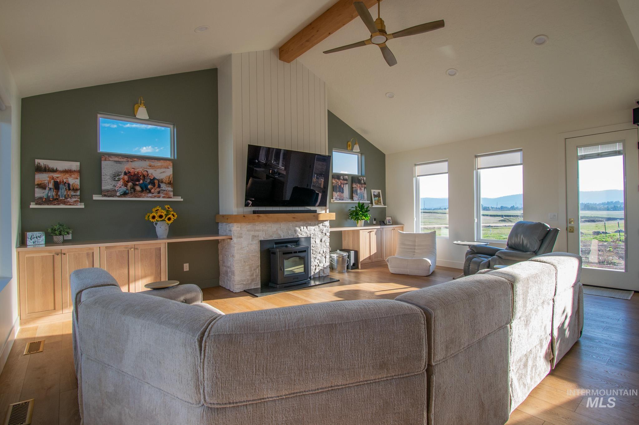 44 Big Moose Road McCall, ID 83638 - Photo 13 of 50 Living room featuring vaulted ceilings, a stone-clad fireplace with a wood mantel, built-in cabinetry, wood-finish flooring, and a ceiling fan