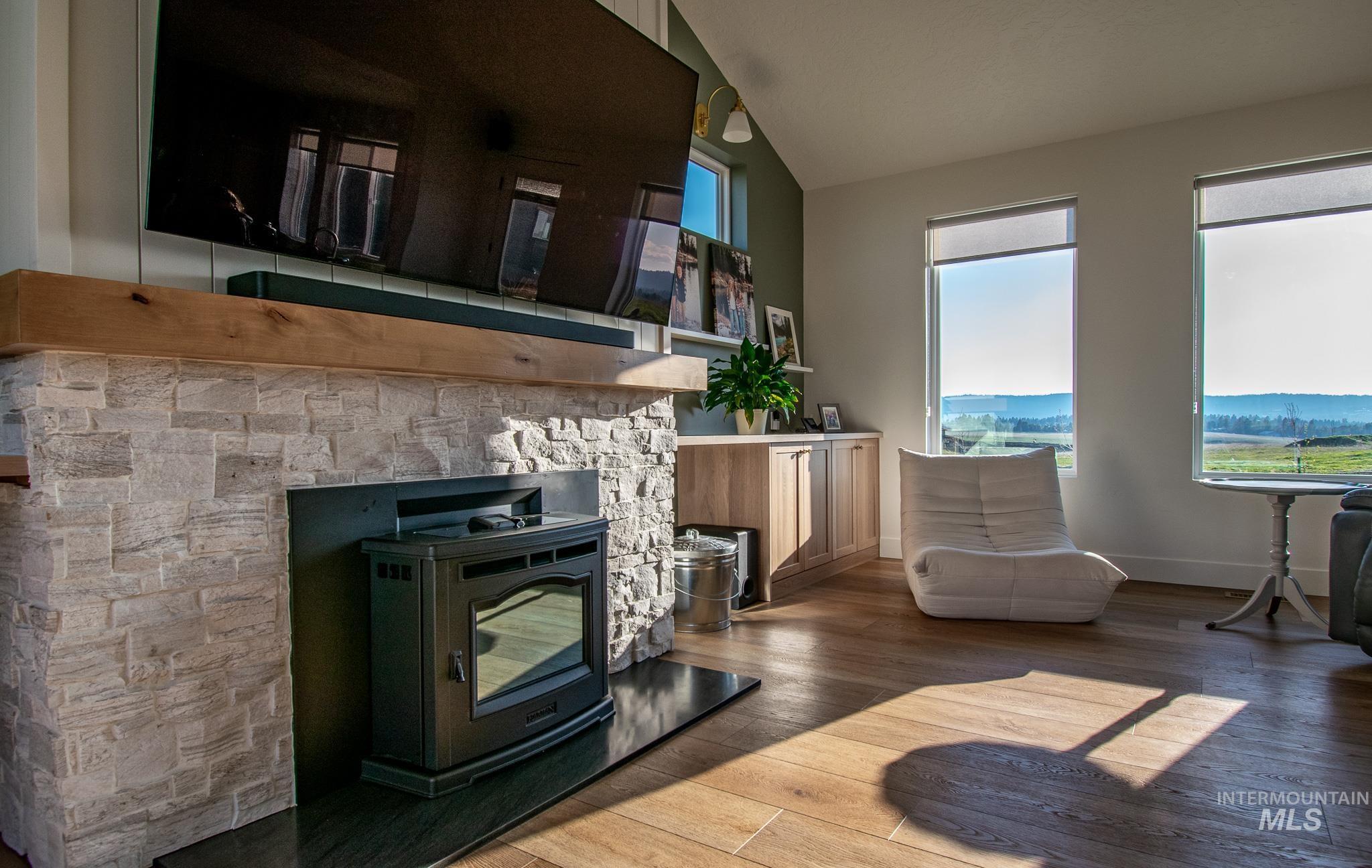 44 Big Moose Road McCall, ID 83638 - Photo 14 of 50 Living area featuring a stone-clad fireplace with a wood mantel, wood-finish flooring, built-in cabinetry, and multiple windows
