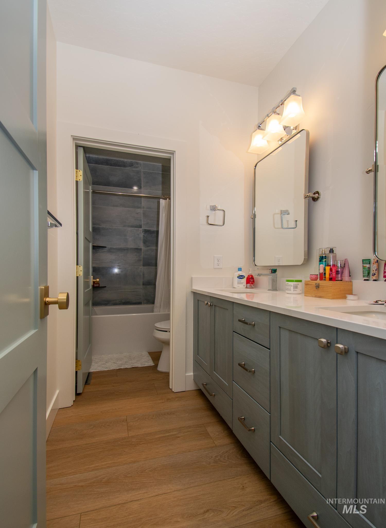44 Big Moose Road McCall, ID 83638 - Photo 26 of 50 Bathroom featuring wood-finish flooring, a double vanity with light gray cabinetry, and a white countertop