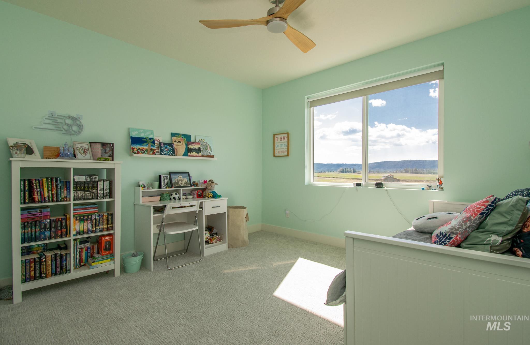 44 Big Moose Road McCall, ID 83638 - Photo 27 of 50 Room featuring a wide window with a landscape backdrop, light green walls, light-toned carpet, and a ceiling fan with wood-finish blades