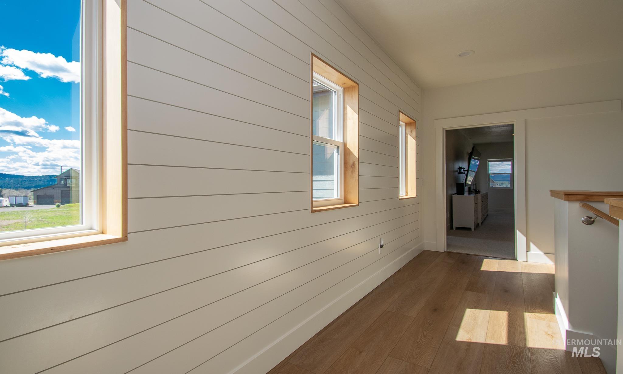44 Big Moose Road McCall, ID 83638 - Photo 30 of 50 Hallway featuring shiplap wall paneling, light wood-finish flooring, multiple windows with wood trim, and recessed lighting