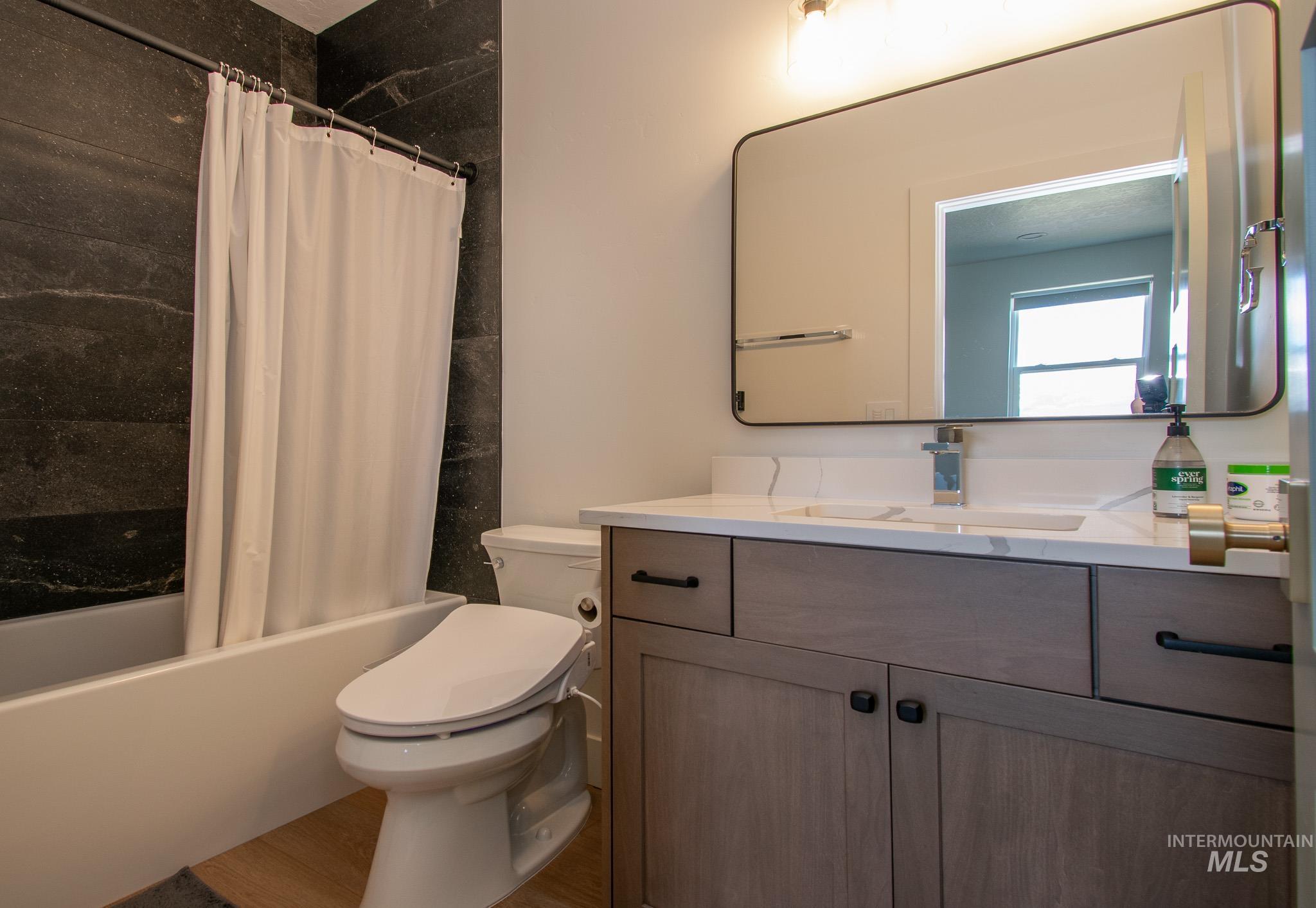44 Big Moose Road McCall, ID 83638 - Photo 36 of 50 Bathroom featuring a white bathtub, dark stone-look shower surround, wood-finish vanity with an integrated sink, white countertop, and rectangular framed mirror