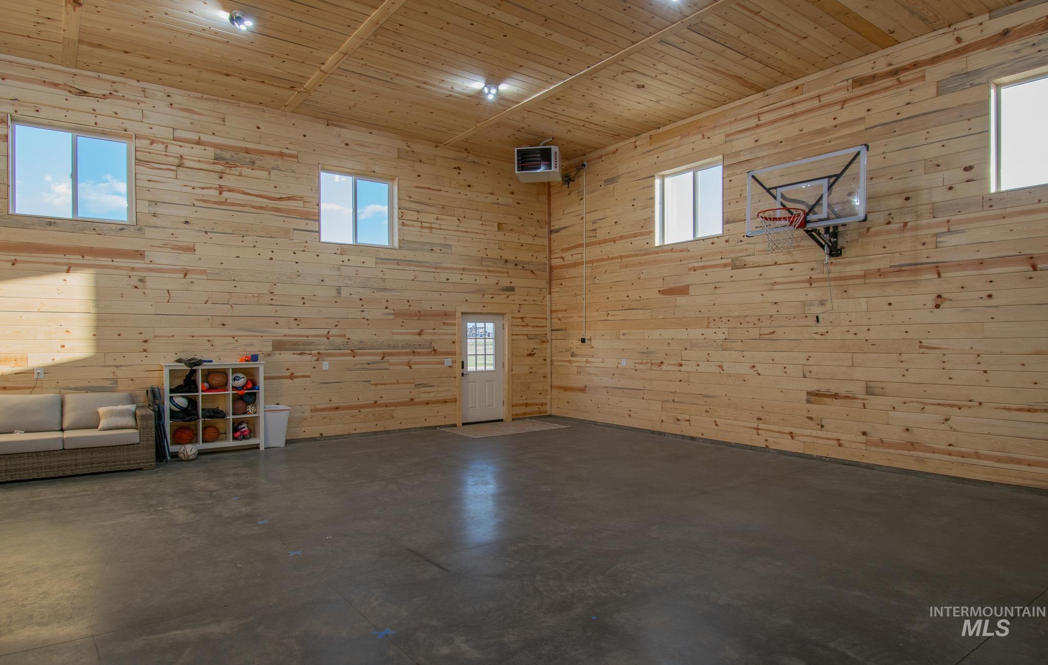 44 Big Moose Road McCall, ID 83638 - Photo 44 of 50 Spacious interior featuring natural wood plank walls and ceiling, high ceilings, four windows, a white entry door with glass panels, and a polished concrete floor