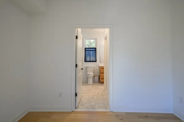 a view of a hallway with wooden floor and a bathroom