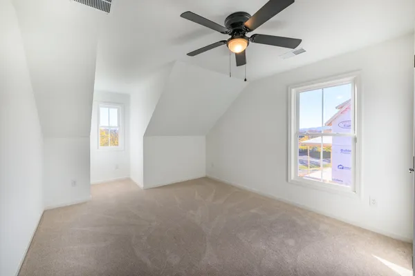 en empty room with windows and ceiling fan