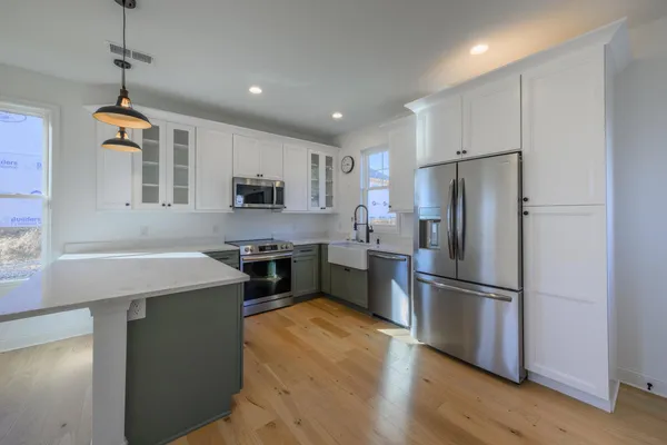 a kitchen with kitchen island a refrigerator wooden floor and a stove top oven