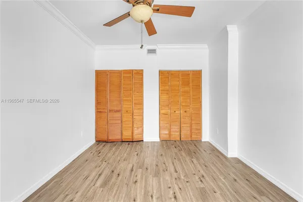 an empty room with wooden floor chandelier fan and windows