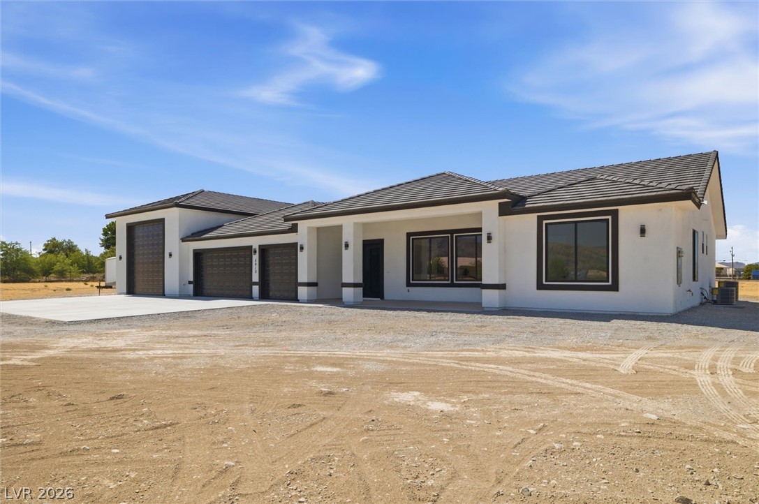 5910 East Kellogg Road Pahrump, NV 89061 - Photo 5 of 58 A modern facade with a striking tile roof and attached garage bays, showcasing contemporary architectural design.