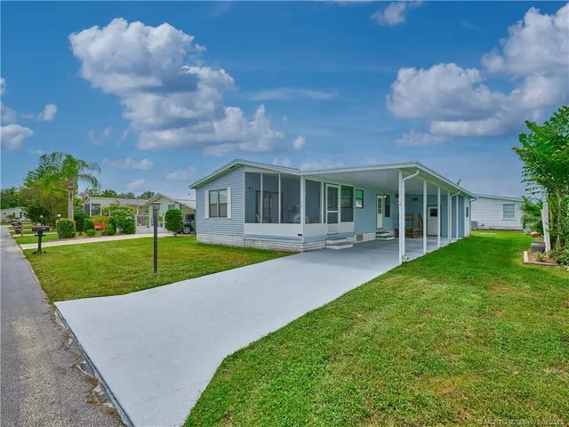 a view of house with a big yard potted plants and large tree