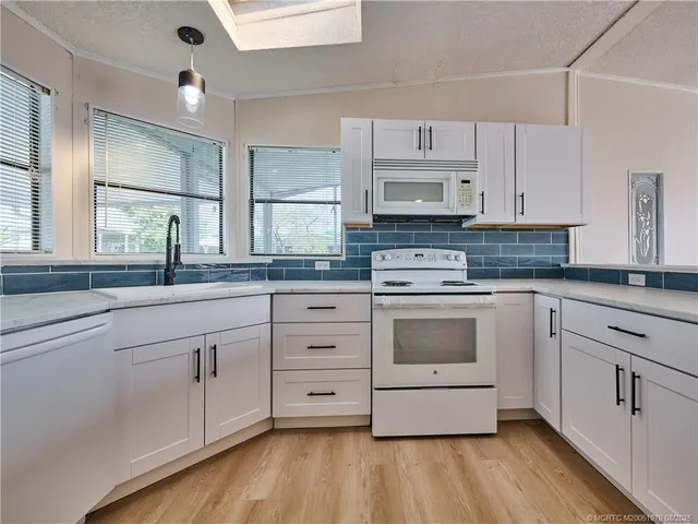 a kitchen with granite countertop white cabinets and white stainless steel appliances