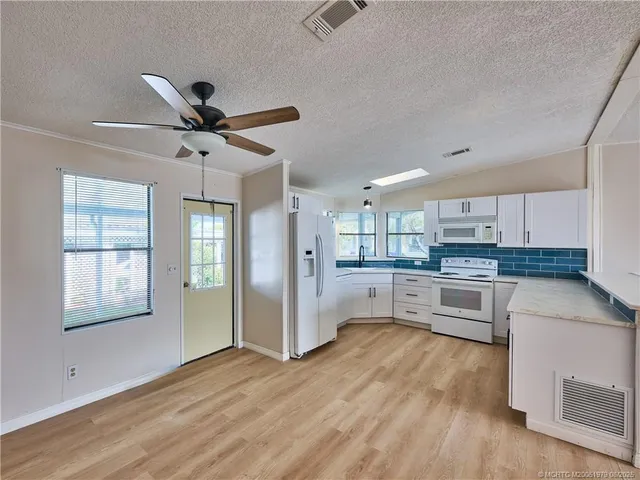 a large kitchen with cabinets wooden floor and stainless steel appliances