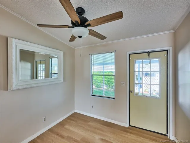 an empty room with wooden floor fan and windows