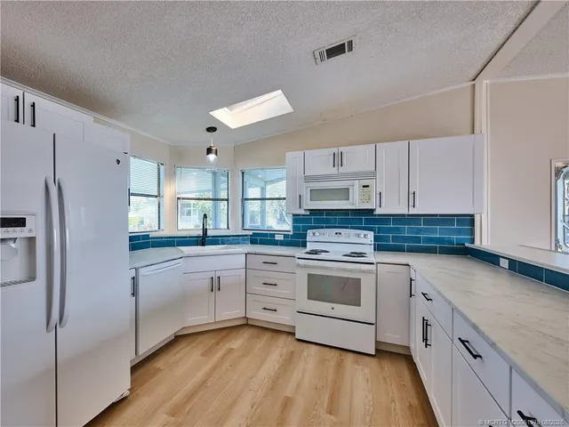 a kitchen with white cabinets and white appliances