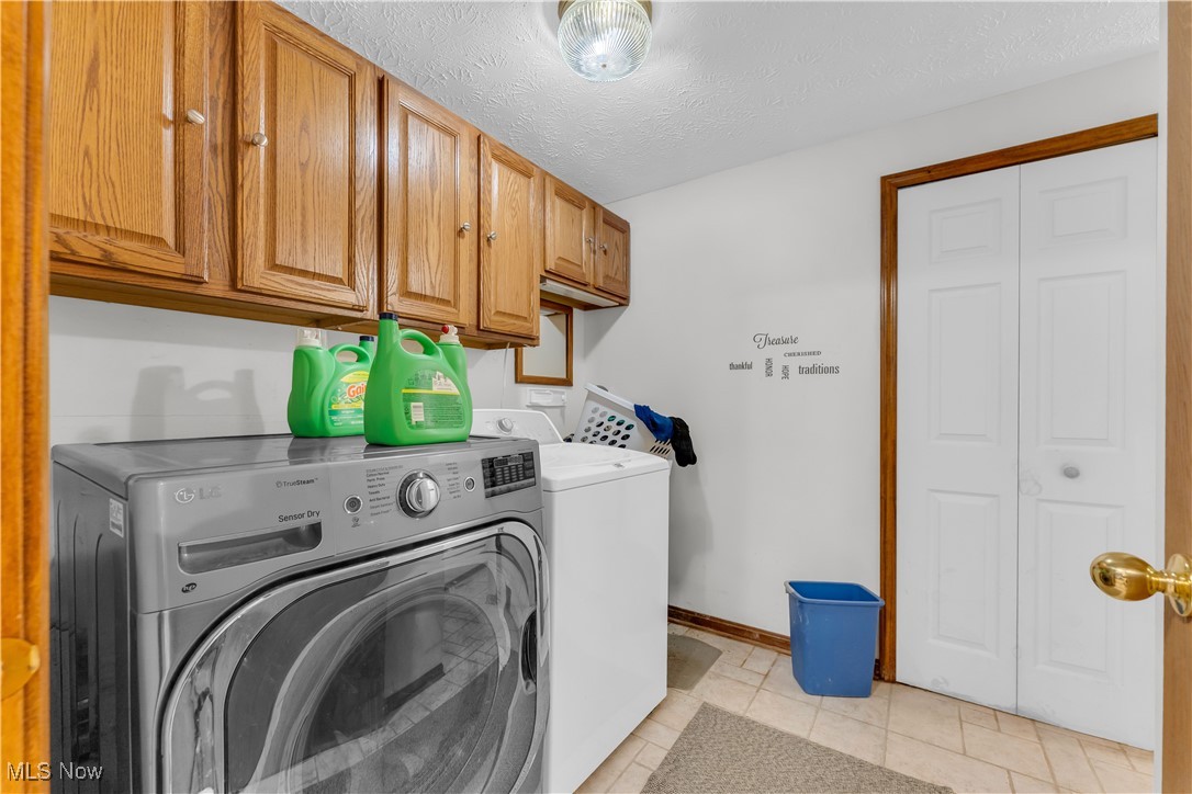 6834 Glendale Road North Ridgeville, OH 44039 - Photo 16 of 37 Laundry area with cabinet space, separate washer and dryer, a textured ceiling, and light tile patterned floors