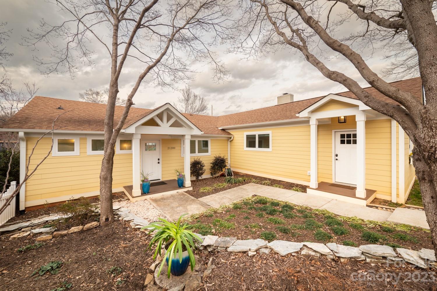 a view of a yard in front of a house with large tree