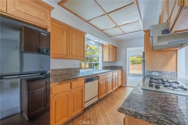 a kitchen with stainless steel appliances granite countertop a sink a stove and a wooden cabinets