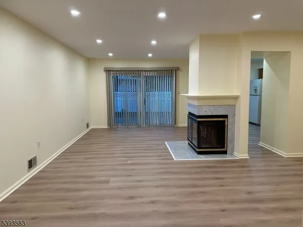 a view of an empty room with wooden floor and a fireplace
