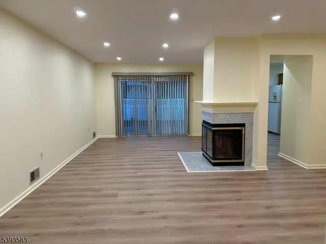 a view of an empty room with wooden floor and a fireplace
