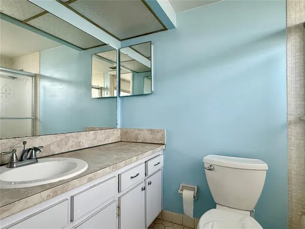 a bathroom with a granite countertop toilet sink and mirror