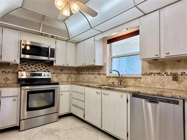 a kitchen with granite countertop a sink stainless steel appliances and white cabinets