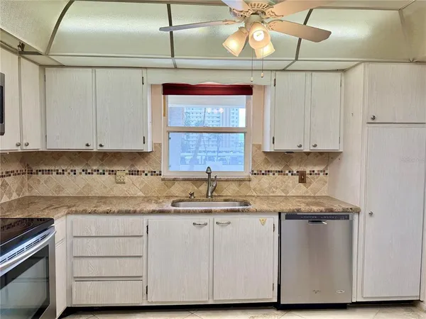 a kitchen with cabinets appliances a sink and a window