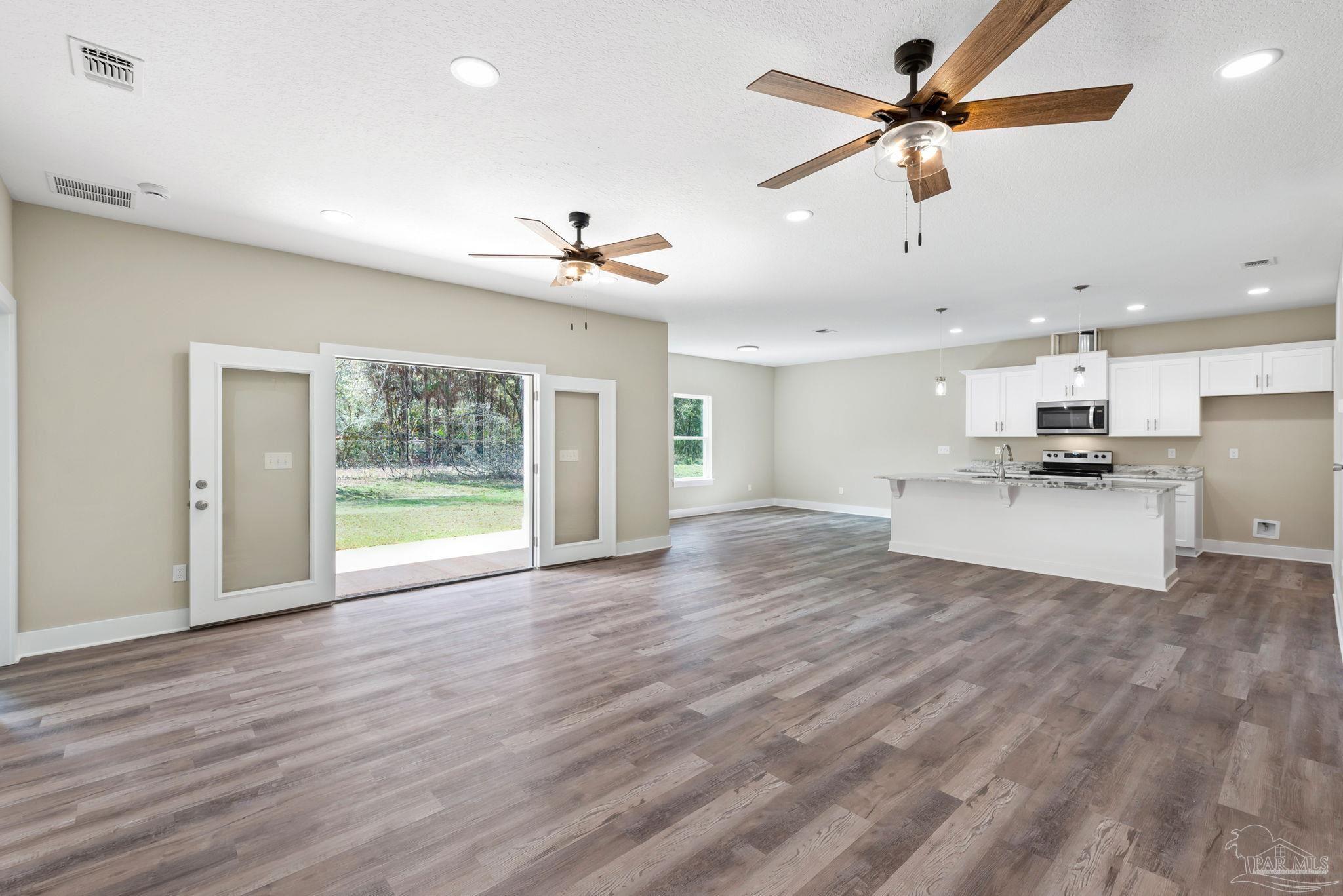 8261 Larson Lane Milton, FL 32583 - Photo 13 of 47 a view of an empty room with a kitchen and ceiling fan
