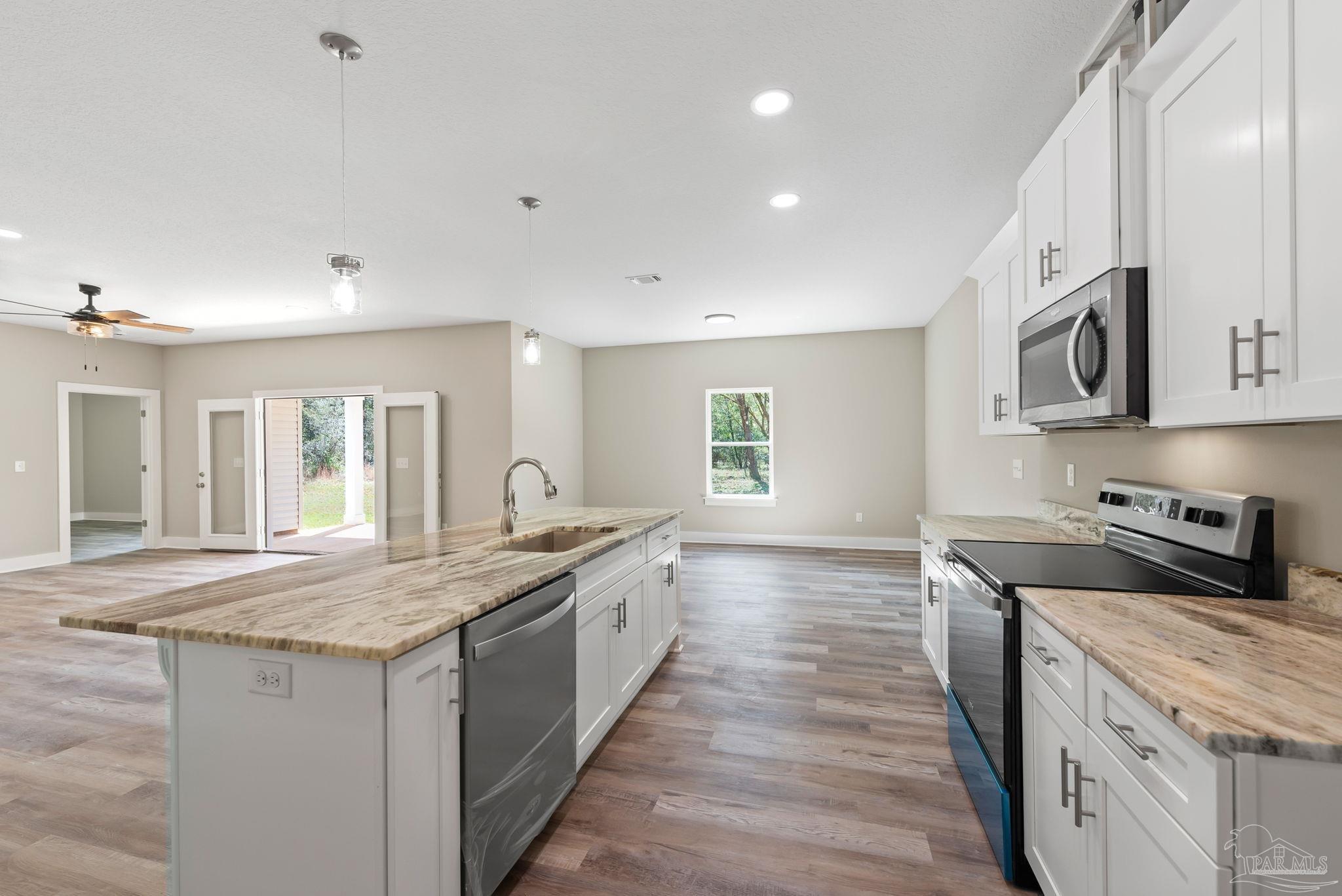 8261 Larson Lane Milton, FL 32583 - Photo 20 of 47 a kitchen with stainless steel appliances granite countertop a sink and dishwasher a stove top oven with wooden floor