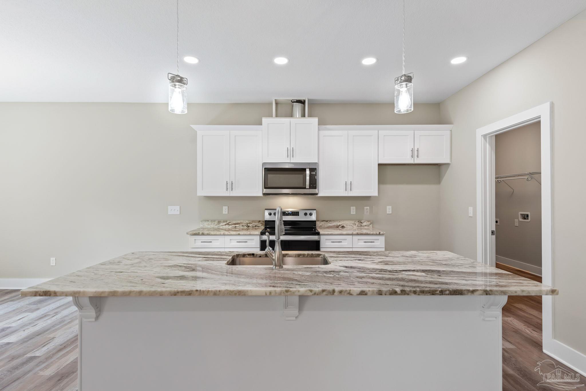 8261 Larson Lane Milton, FL 32583 - Photo 21 of 47 a kitchen with kitchen island granite countertop a sink stainless steel appliances and white cabinets