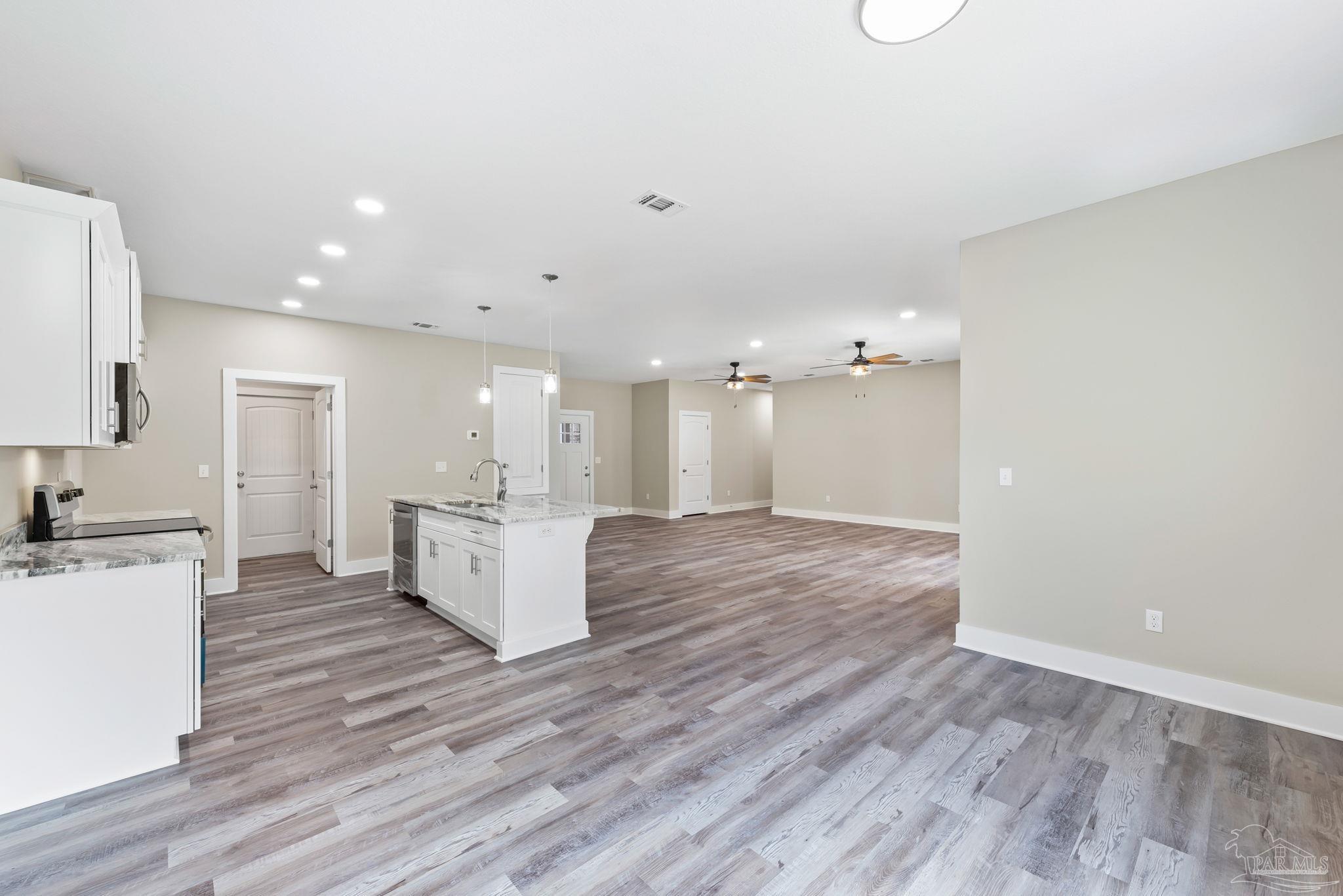 8261 Larson Lane Milton, FL 32583 - Photo 26 of 47 a view of a kitchen with kitchen island wooden floors appliances and cabinets